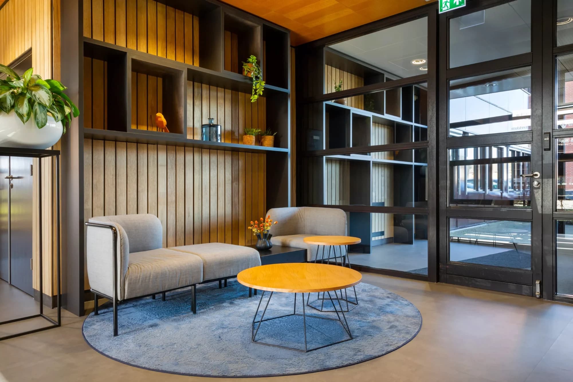 Ontvangstruimte met houten wandbekleding, twee zitbanken en een rond vloerkleed